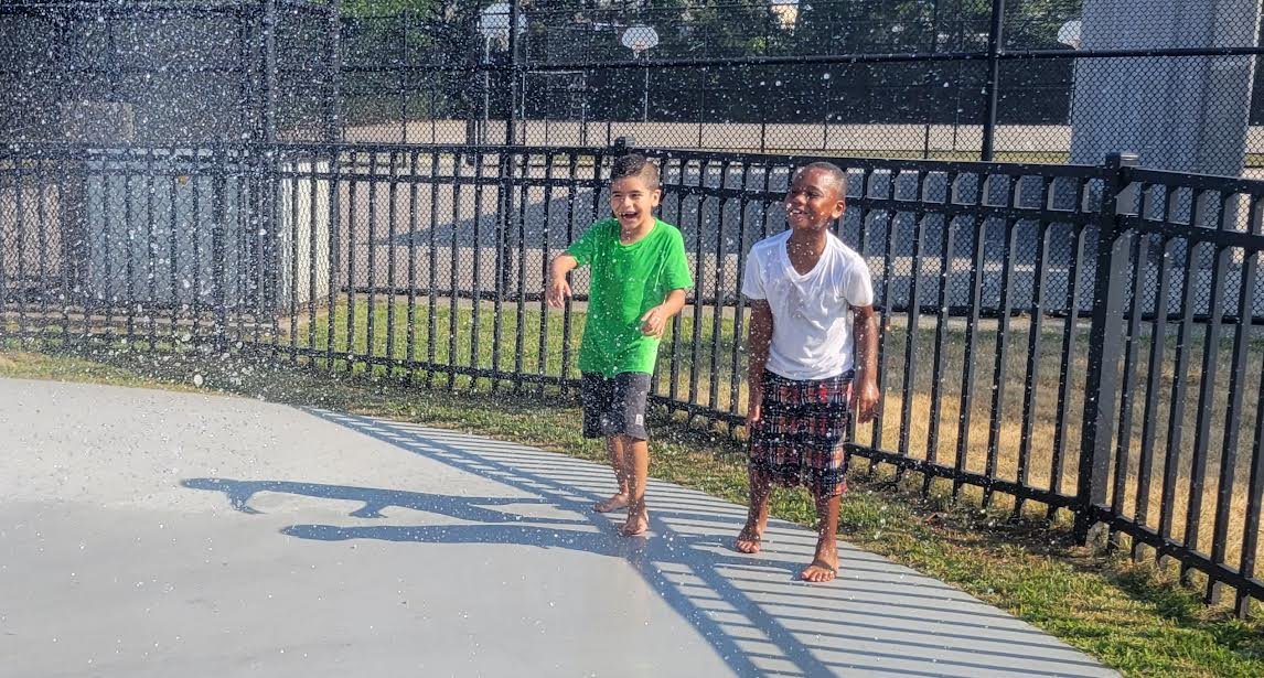 Kids enjoy the sprinklers at the Unity Day event at Robert Rowley Park in Bellport.